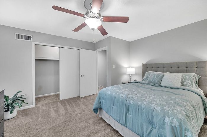 Inviting bedroom featuring a plush bed with floral bedding, elegant lighting, and ample closet space, perfect for relaxation and comfort.
