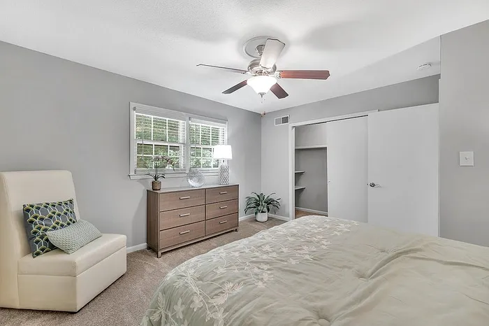 Inviting bedroom with plush bedding, modern dresser, and serene natural light enhancing the tranquil atmosphere.