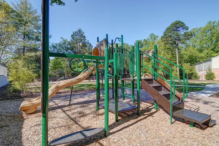 Inviting outdoor playground featuring slides and climbing frames surrounded by lush greenery, perfect for family fun.