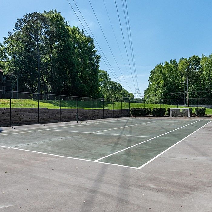 Inviting outdoor tennis court surrounded by lush greenery, perfect for sports enthusiasts seeking leisure and recreation.