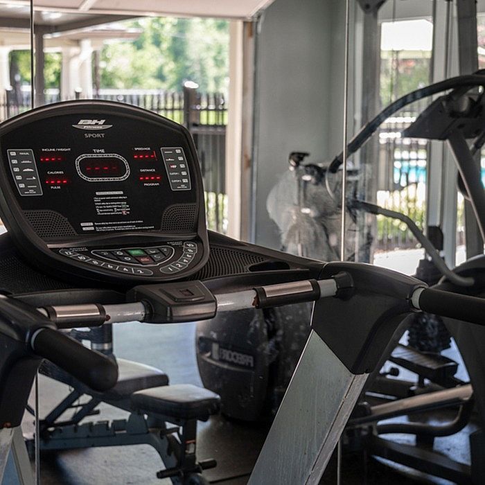 Modern fitness center featuring state-of-the-art treadmill with scenic view of outdoor pool area.