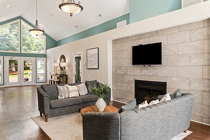 Elegant living room with high ceilings, large windows, cozy gray sofas, modern fireplace, and abundant natural light.