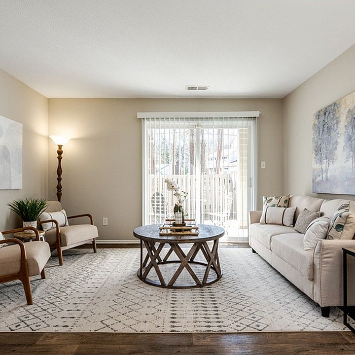 Inviting living room with elegant decor, featuring plush seating, a round wooden coffee table, and natural light streaming through glass doors.