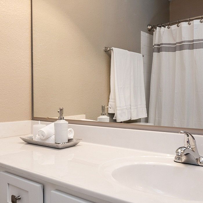 Elegant bathroom with sleek fixtures, large mirror, and modern shower curtain offering a tranquil retreat.
