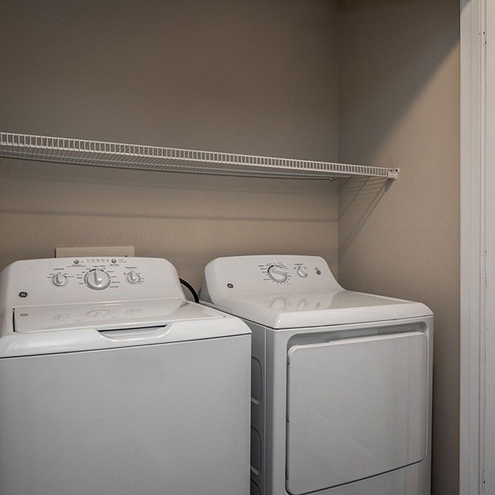 Modern laundry room featuring a sleek washer and dryer set with convenient overhead shelving.