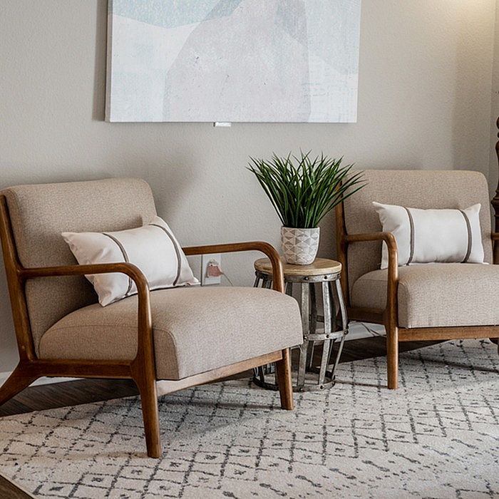 Cozy living area with elegant armchairs, soft cushions, chic round table, and stylish decor plant, perfect for relaxation.