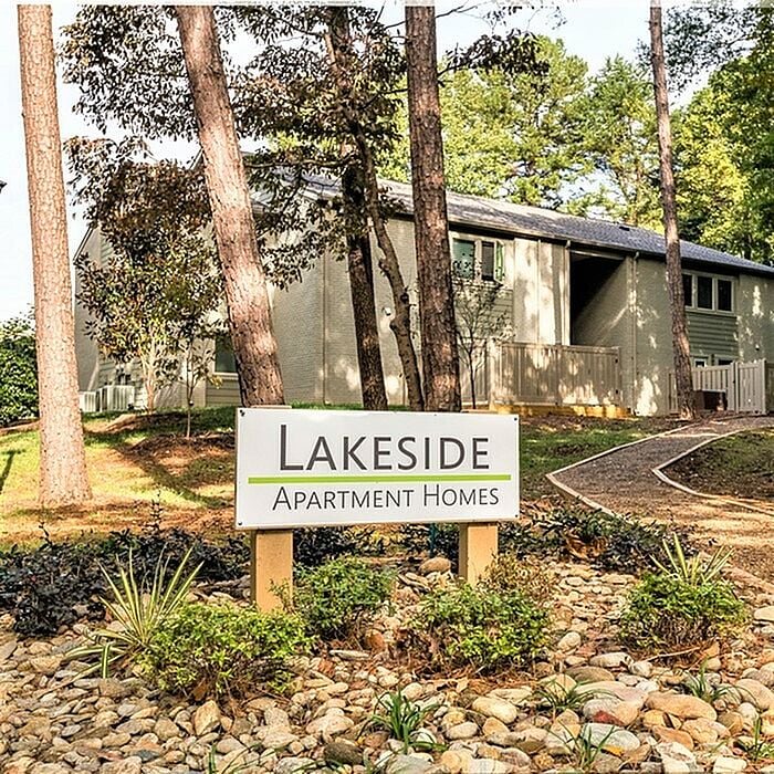 Charming Lakeside Apartment Homes nestled among tall trees and natural landscaping, offering a serene and inviting atmosphere.