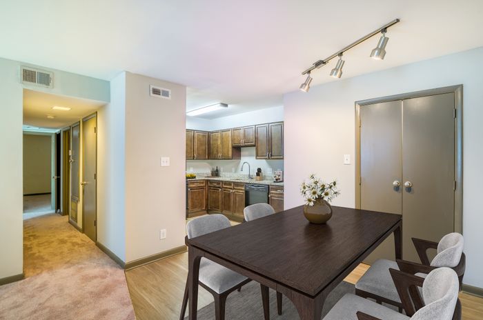 Inviting apartment interior with a cozy dining area adjacent to a modern kitchen featuring sleek wooden cabinets and stylish lighting.