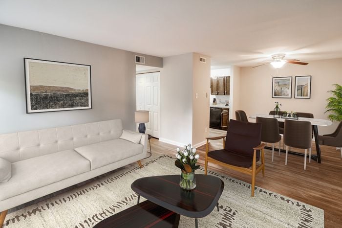 Modern living room with elegant decor, featuring a comfortable beige sofa, chic artwork, and a cozy dining area with a sleek table set in an open-plan layout.