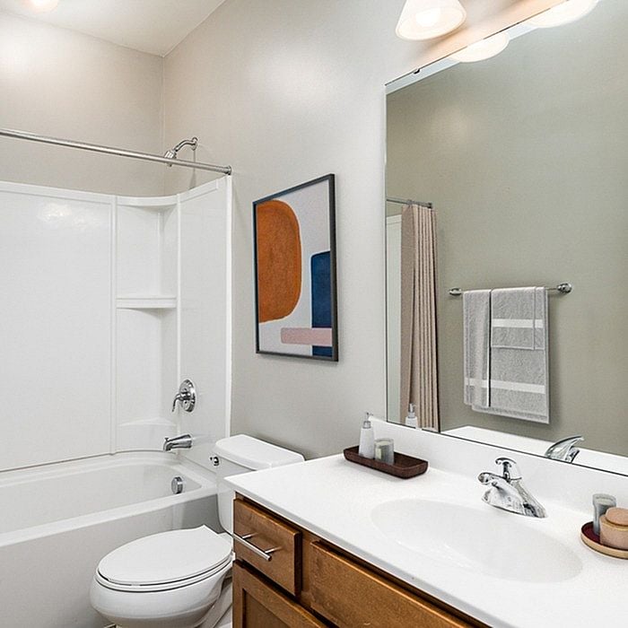 Contemporary bathroom with sleek white fixtures, modern art, and elegant lighting, ideal for a stylish apartment.