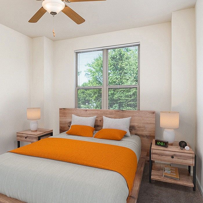 Inviting bedroom with modern decor, featuring a comfortable bed with bright orange accents, natural light through a large window, and stylish wooden furniture.