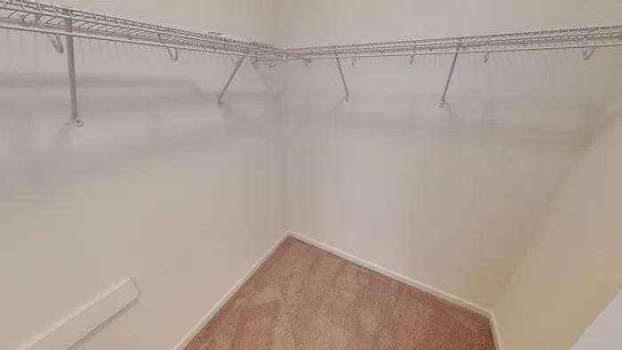 Spacious walk-in closet with sleek wire shelving, perfect for organizing your wardrobe in a cozy, carpeted space.