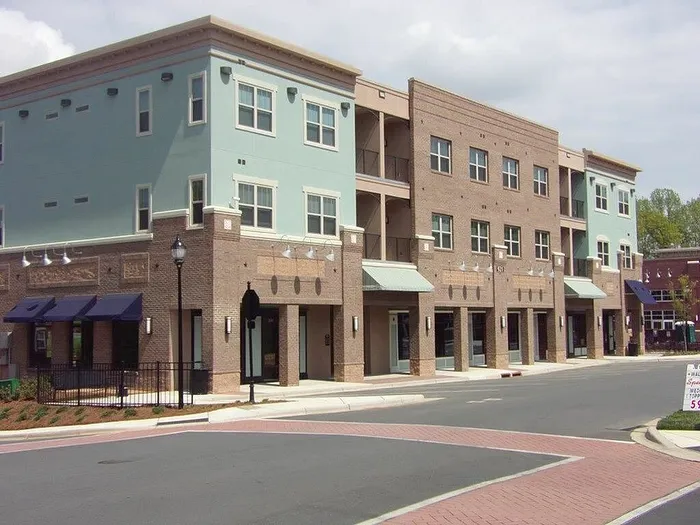 Modern mixed-use development with stylish brick facade, large windows, and inviting retail spaces on a serene street corner.