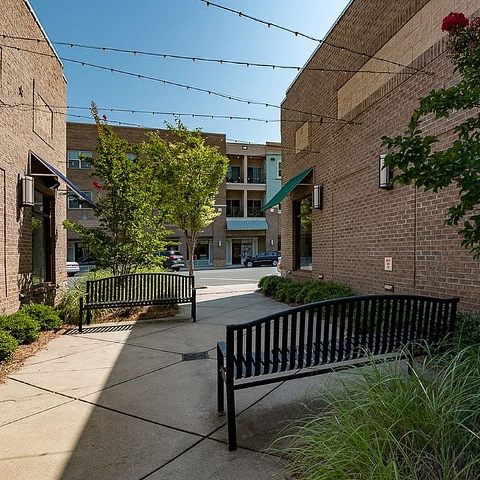 Charming apartment courtyard with stylish benches, lush greenery, and inviting pathways under elegant string lights.