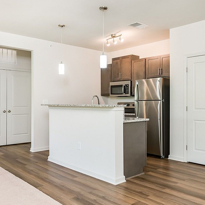 Modern kitchen featuring sleek stainless steel appliances, granite countertops, and elegant pendant lighting, all surrounded by rich wood cabinetry.