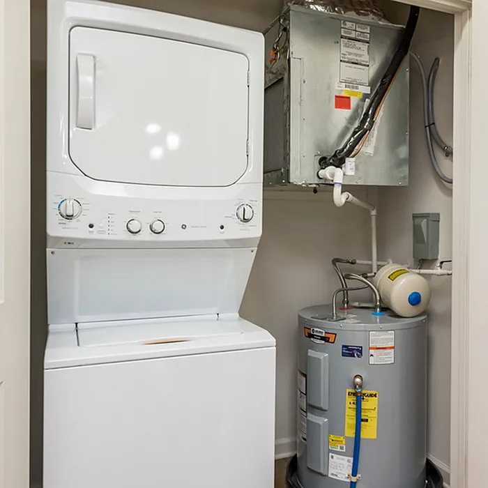 Modern laundry room with a sleek stacked washer and dryer set, complemented by energy-efficient water heater.