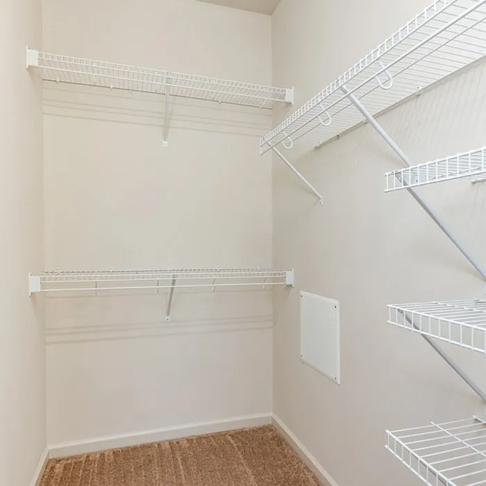Spacious walk-in closet with sleek white shelving, perfect for organized storage and maximizing space.
