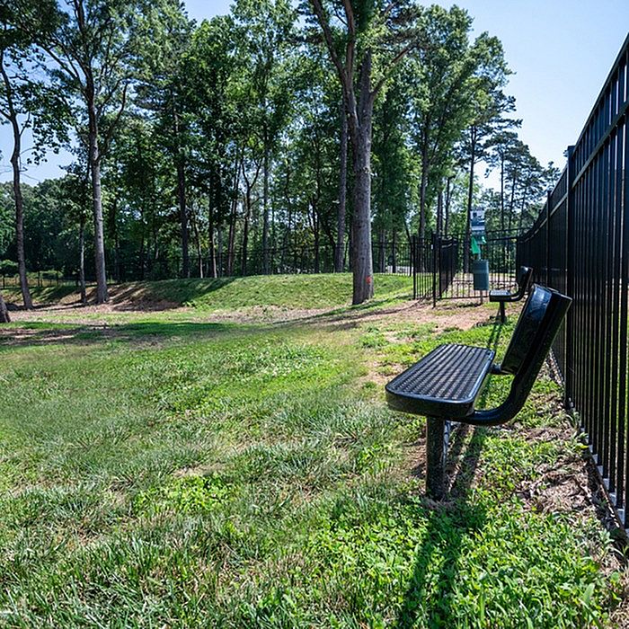 Serene gated park area with lush greenery and comfortable benches, perfect for relaxation.