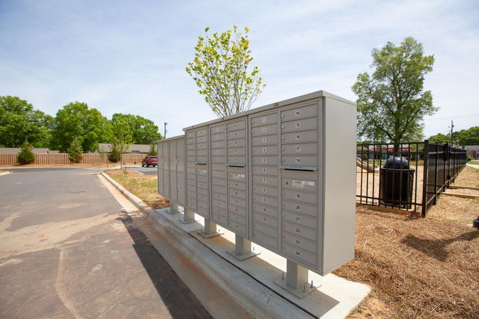 Community mailboxes in a serene neighborhood setting with lush greenery and a sunny sky.