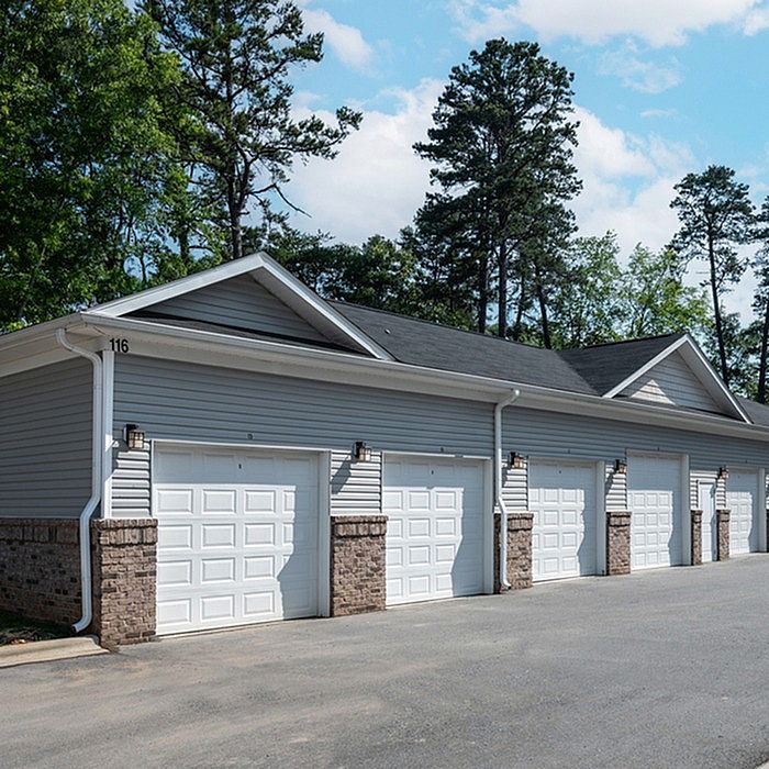Charming row of modern garages in a tranquil neighborhood setting, surrounded by lush greenery and blue skies.