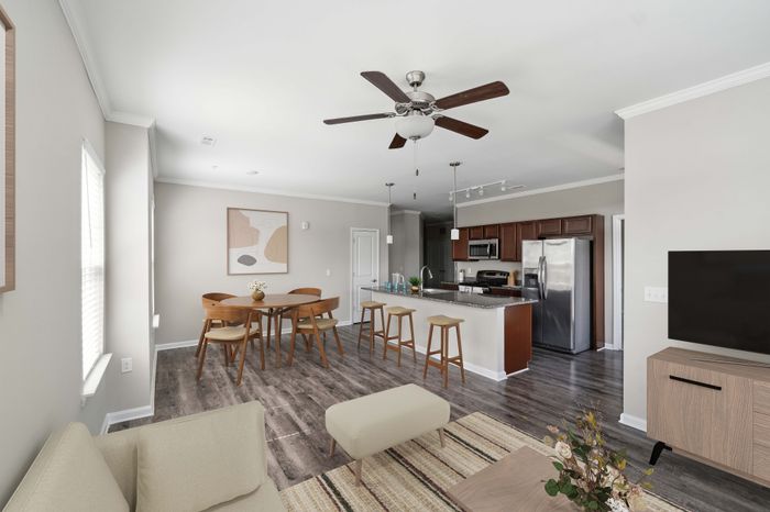 Bright modern living area featuring an open-concept kitchen with stainless steel appliances, cozy dining space, and elegant wood flooring.