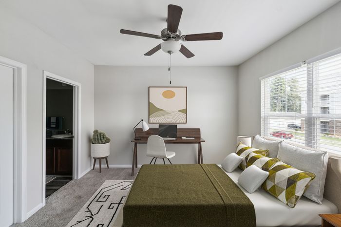 Modern bedroom with elegant decor, featuring a cozy bed, chic pillows, a stylish desk, and abundant natural light.