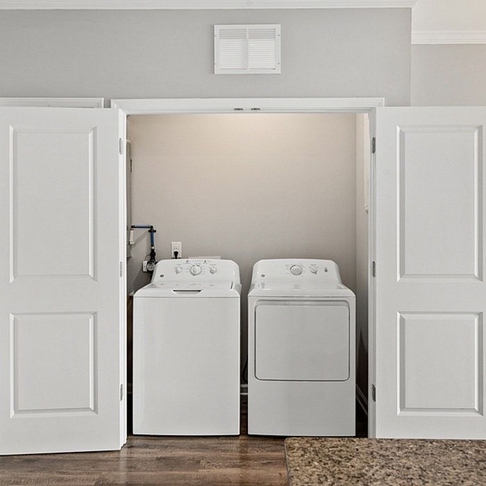 Modern laundry area with sleek white washer and dryer, tucked neatly within elegant white folding doors.