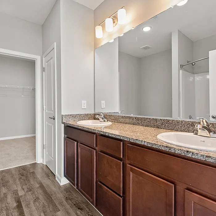 Modern bathroom with elegant dual sinks, granite countertop, and sleek cabinetry, offering a touch of luxury.