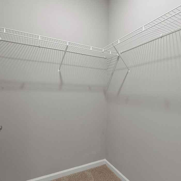 Spacious and bright walk-in closet featuring sleek white shelving and neutral carpet, perfect for organized storage.