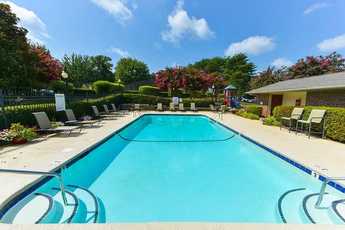 Inviting outdoor swimming pool with plush lounge chairs and vibrant landscaping under a clear blue sky, perfect for relaxation and leisure.