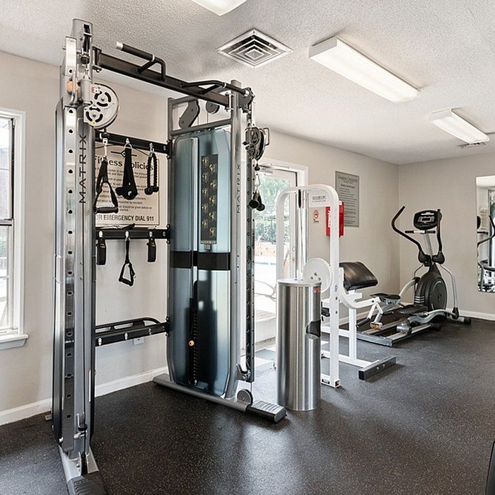 Bright, well-equipped gym featuring modern fitness machines, including a multifunctional trainer, exercise bike, and strength equipment in a welcoming apartment community.