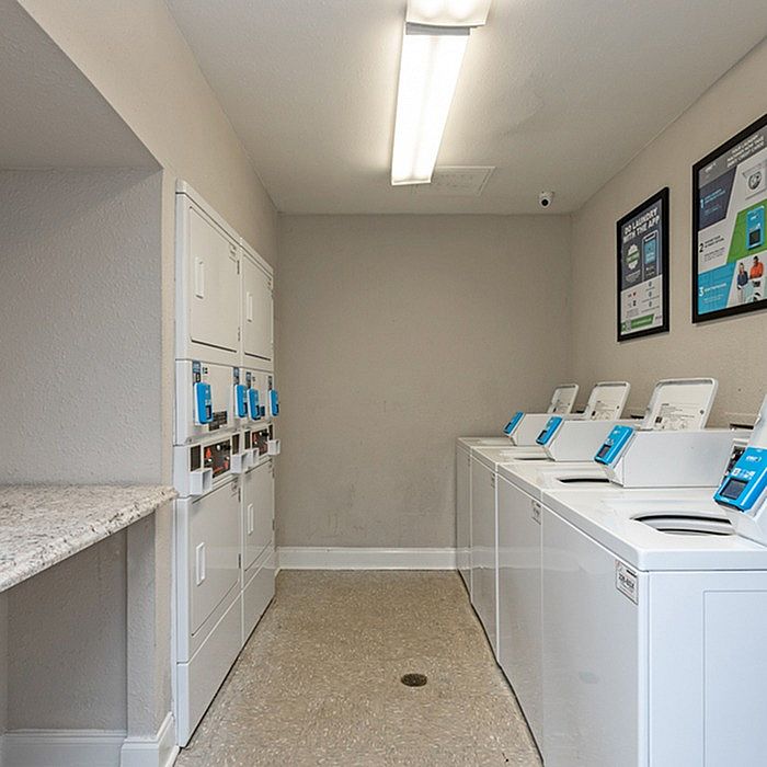 Bright and modern laundry room with multiple washing machines, dryers, and convenient folding counter.