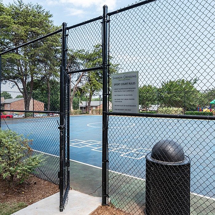 Inviting outdoor sports court with vibrant blue surface, fenced for safety, nestled within lush greenery.