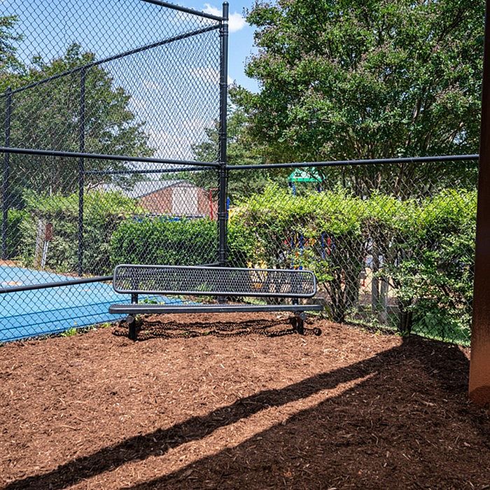 Inviting outdoor seating area by the tennis courts, surrounded by lush greenery and vibrant trees.