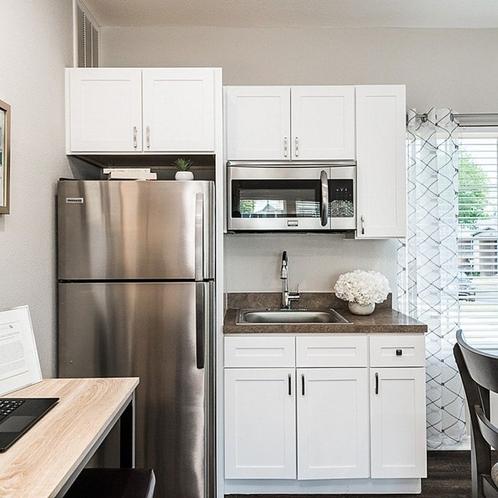 Contemporary kitchen featuring sleek stainless steel appliances, elegant white cabinetry, and a cozy dining nook with a view.