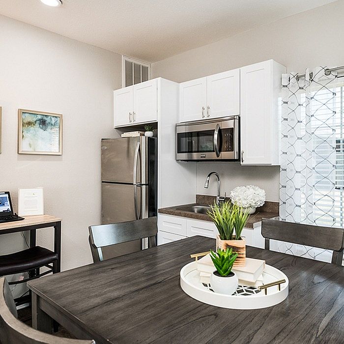 Modern kitchen featuring sleek stainless steel appliances, elegant white cabinets, and a cozy dining area with stylish decor.