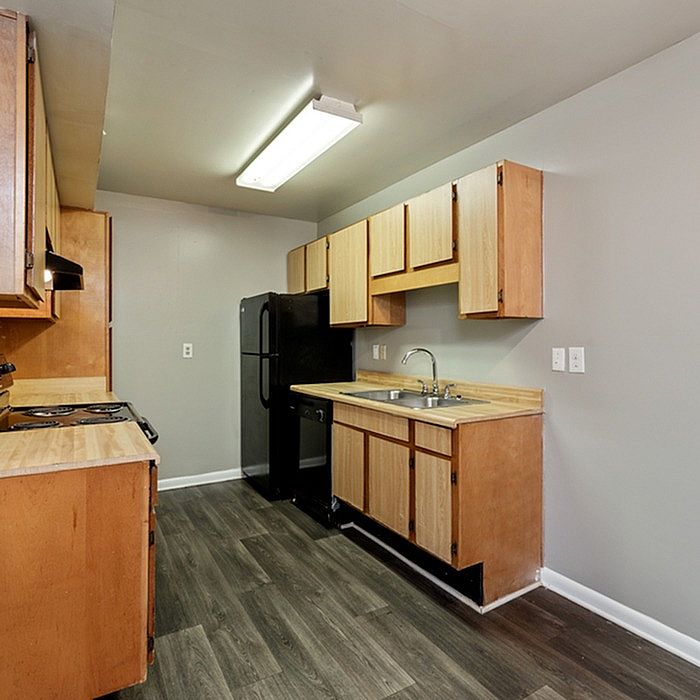Bright and inviting kitchen with sleek wooden cabinets, modern fixtures, and elegant dark flooring.