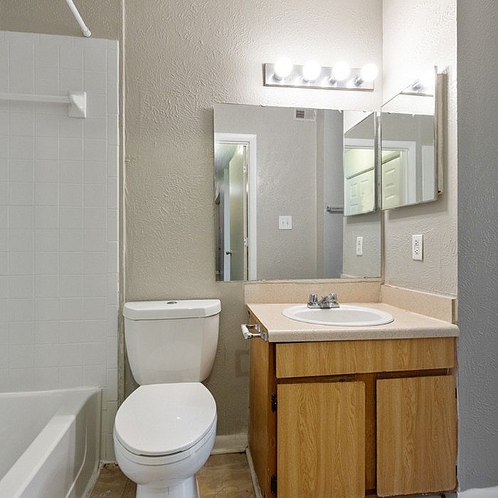 Modern bathroom with bright lighting, elegant vanity, and pristine bathtub, designed for comfort and style.