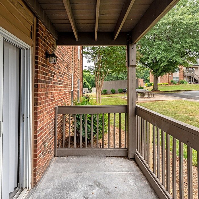 Charming apartment patio with wooden railing, offering a serene garden view and ample natural light.