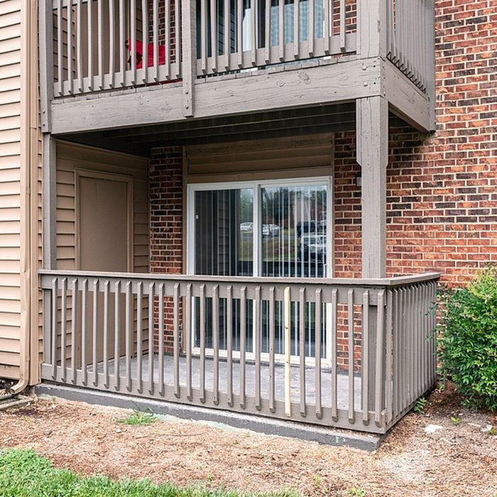 Charming outdoor patio with wooden railing and sliding glass doors, perfect for relaxing evenings.