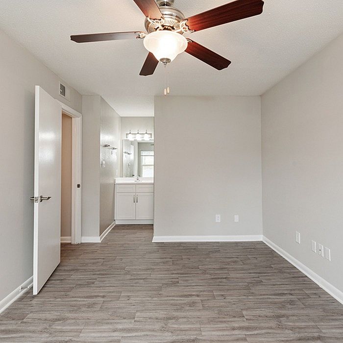 Elegant bedroom with sleek laminate flooring, ceiling fan, and an en-suite vanity showcasing modern living.