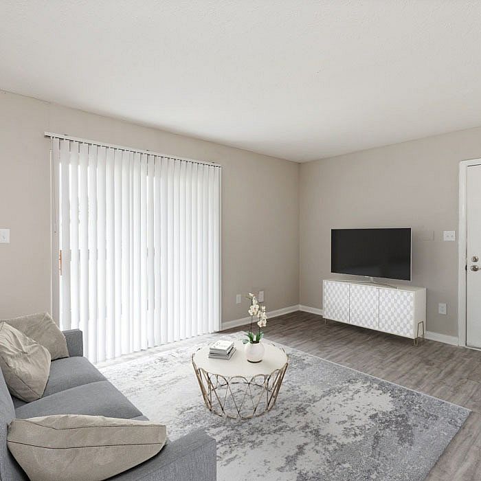 Bright and modern living room featuring a cozy gray sofa, stylish coffee table, and sleek TV setup, with abundant natural light from large sliding doors.