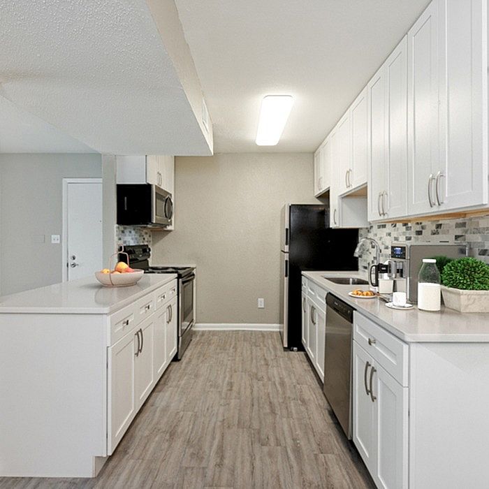 Bright and modern kitchen with sleek white cabinetry, stainless steel appliances, and elegant wood flooring.