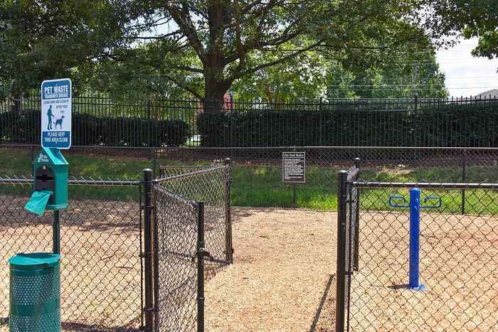 Inviting pet-friendly area featuring a clean, fenced-in dog park with waste disposal stations and beautiful surrounding greenery.
