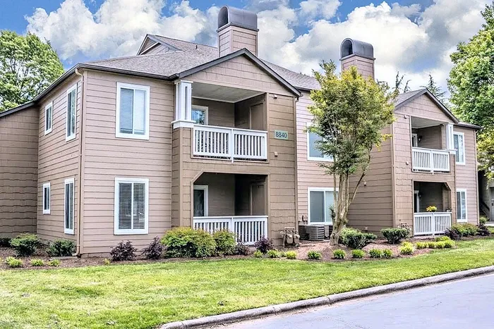 Inviting exterior of a modern apartment complex with charming balconies, lush greenery, and a welcoming atmosphere.