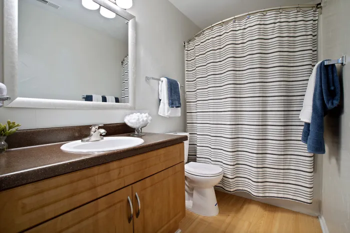 Elegant bathroom with modern fixtures, warm wood cabinetry, and a stylish striped shower curtain.