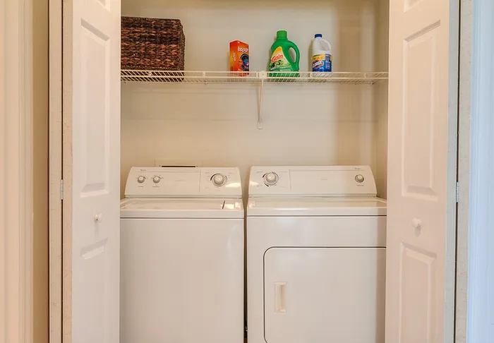 Convenient in-unit laundry space featuring a modern washer and dryer with ample shelf storage.