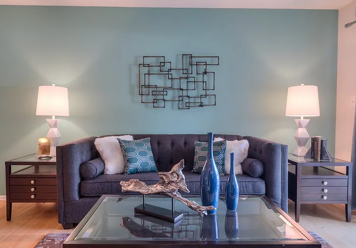 Chic living room with a modern gray sofa, decorative pillows, geometric wall art, and elegant side tables with stylish lamps.