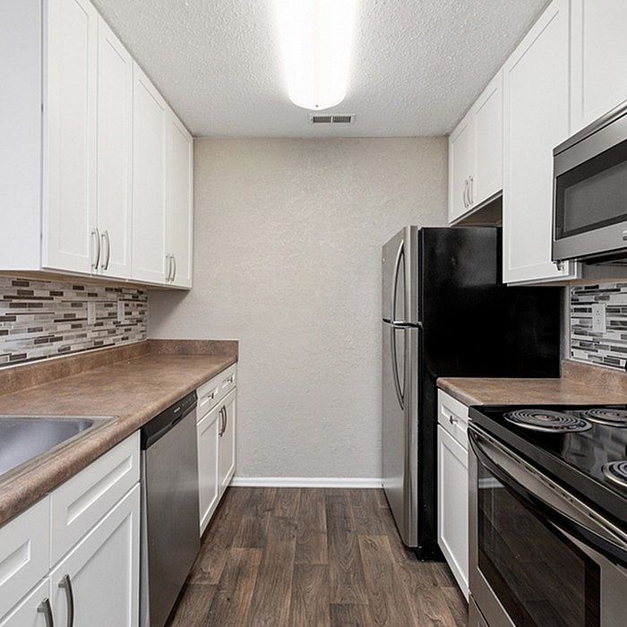 Modern kitchen with sleek stainless steel appliances, elegant tile backsplash, and rich wood flooring.