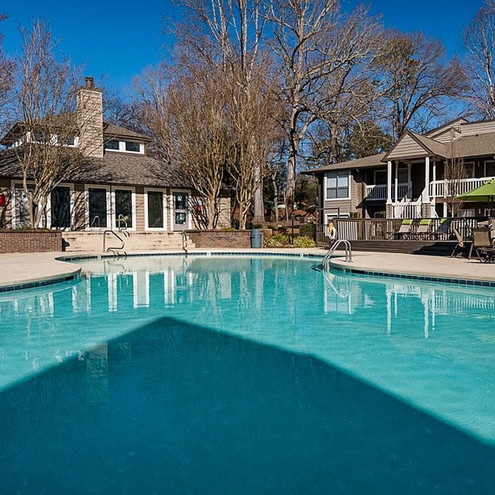 Inviting residential swimming pool surrounded by trees and charming houses, perfect for relaxation and leisure.